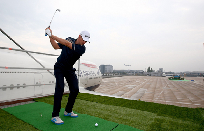 Golfer Justin Rose  plays a shot from the wing of a British Airways Boeing